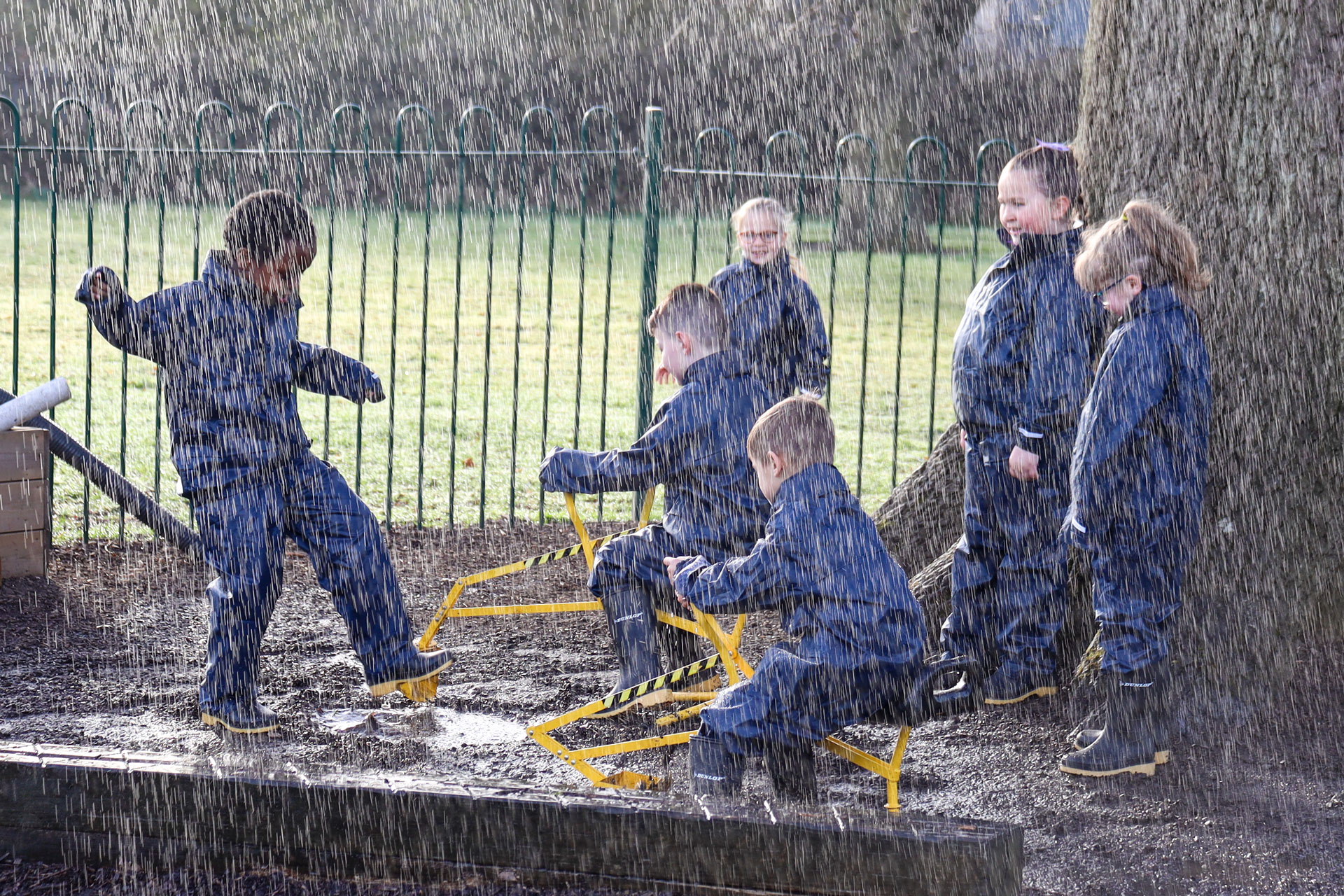 Schoolchildren playing in the rain and mud